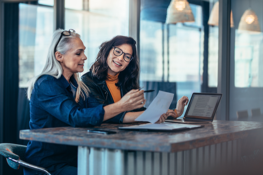 two woman discussing data on spreadsheet