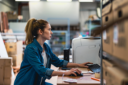 woman typing on computer in warehouse