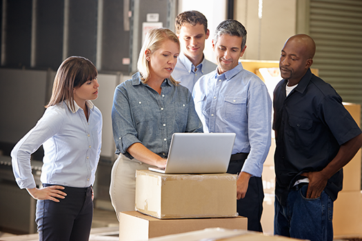 coworkers looking at laptop in warehouse
