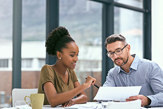 man and woman coworkers looking at report in office