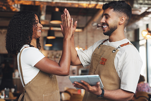 man and woman restaurant workers high fiving each other