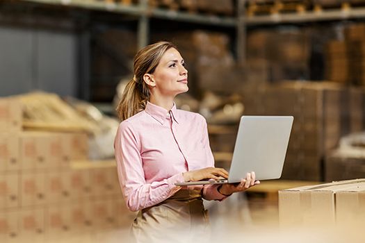 woman in warehouse looking at laptop