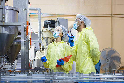 man and woman looking at machinery in food plant