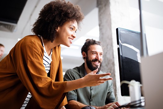 man and woman in office looking at computer