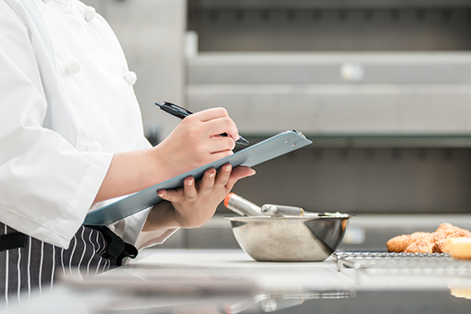 food safety auditor writing on clipboard
